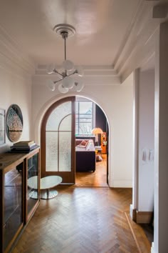 an arched doorway leading to a living room with hardwood floors and hard wood flooring