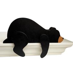 a black bear laying on top of a white shelf