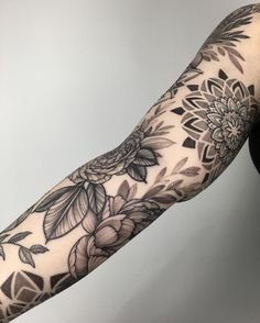 a woman's arm with flowers and leaves on it