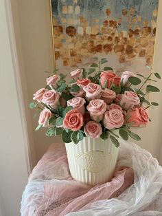 a white vase filled with pink roses on top of a table