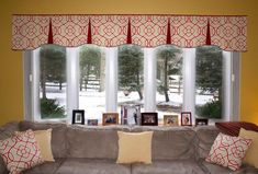 a living room filled with furniture and windows covered in valance drapes on top of them