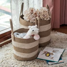 two baskets with stuffed animals in them sitting on a rug next to a book and window