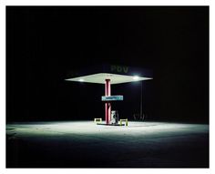 an empty gas station at night with the lights on and no one around it,