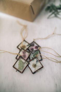 four small pictures hanging from strings on a white table with a box in the background