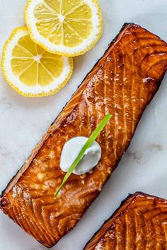 two salmon fillets with sour cream and lemon wedges on the side for garnish