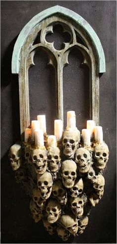 a bunch of skulls that are sitting on a wall next to a window with candles in it