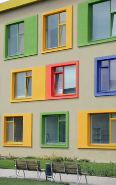 a multi - colored building with benches in front of it and windows on the side