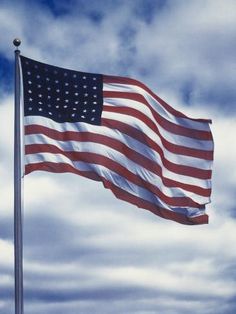 an american flag waving in the wind on a cloudy day with blue sky and white clouds