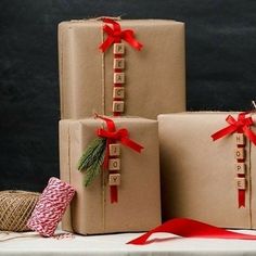 three presents wrapped in brown paper and tied with red ribbon are sitting on a table