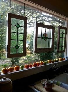 three stained glass windows with fruit on the window sill and sink in front of them