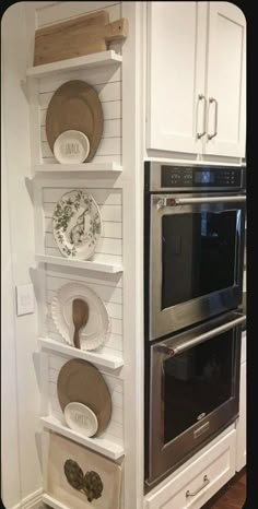 a kitchen with white cabinets and shelves filled with dishes on top of each shelf in front of an oven