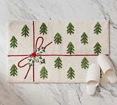 a christmas present wrapped in white paper with green trees on it