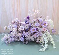 a bunch of flowers that are sitting on the ground in front of a curtained wall