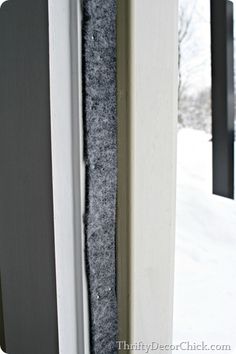 an open door with a black and white curtain on it's side in the snow