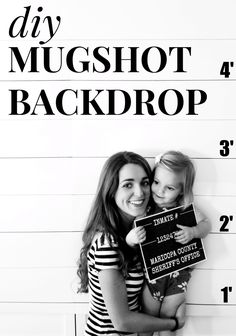 a woman holding a small child in front of a mugshot sign that says, diy mugshot back drop