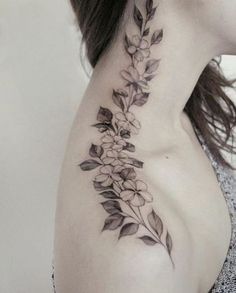 a woman's neck with flowers and leaves tattoo on her left side ribcage