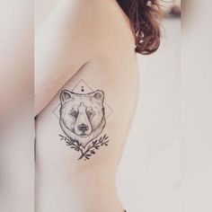 a woman with a bear tattoo on her shoulder and chest, holding onto the arm