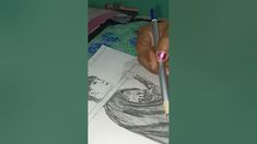 a person holding a pencil and drawing on paper with another hand next to it,