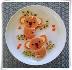 two stuffed koala bears on a white plate with orange and green hearts around them