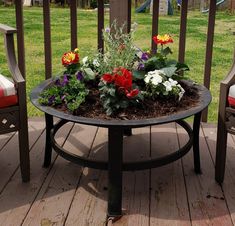 a table that has some flowers in it on a deck with two chairs around it