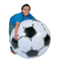 a young boy is posing with a giant soccer ball