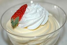 a dessert with whipped cream and strawberries in a glass bowl