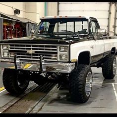 the truck is parked in the garage with its big tires on it's flatbed