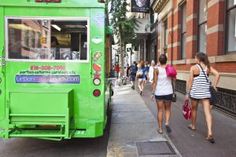 people walking on the sidewalk near a green food truck