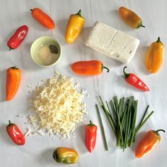 several different types of food are arranged on a white tablecloth, including cheese and peppers