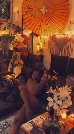 a woman sitting on a couch with flowers and candles in front of an umbrella over her head