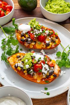 two stuffed sweet potatoes with guacamole, salsa and sour cream on the side