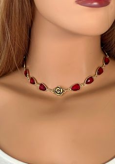 This gorgeous gold choker necklace features a strand of gold plated ruby red crystal bezels links. A gold pewter rose link forms a focal point at the front of the necklace. It closes with a gold filled lobster clasp.  The choker extends from 14 to almost 16 inches with a gold filled chain that ends in a little faceted hematite bead.  This elegant choker is a beauty worn on its own but also lovely when layered with gold chain. Your necklace will arrive in an organza gift bag with a gemstone attribute description and an inspirational window message card. Here is a link to all the gemstone necklaces (the Anne Choi necklaces are in a separate link): https://www.etsy.com/shop/ApsaraJewelryDesigns?ref=seller-platform-mcnav&section_id=13929381 Gold Choker For Valentine's Day Party, Elegant Choker, Gemstone Necklaces, Red Jewelry, Gold Choker Necklace, Crystal Choker, Gold Choker, Hematite Beads, Layering Necklace