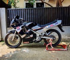 a motorcycle is parked in front of a fence with a chain on the ground next to it