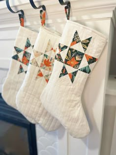 three quilted christmas stockings hanging from hooks