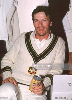 a man sitting down holding a can of beer