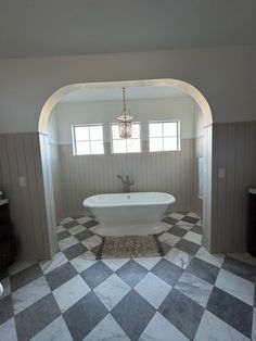 a bathroom with a checkered floor and an arched doorway leading to the bathtub