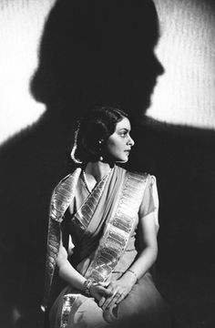 a black and white photo of a woman sitting in front of a man's shadow