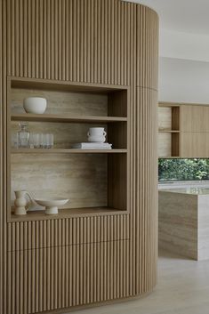 a wooden shelf in the middle of a room with bowls and cups on top of it