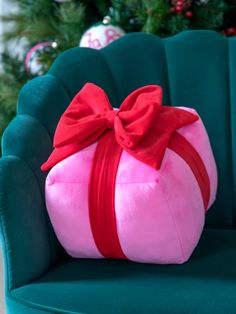 a green chair with a pink and red pillow wrapped in a red ribbon on it