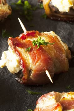 bacon wrapped in cheese and garnished with parsley on a black plate,