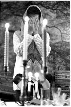 a woman covering her face in front of candles