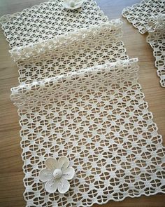 two pieces of white crocheted fabric with flowers on them