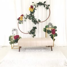 a bench with flowers and greenery on it in front of a white curtained backdrop