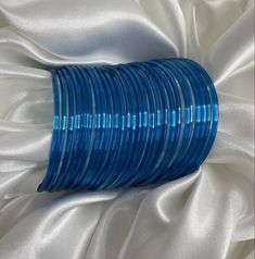 a stack of blue glass bangles sitting on top of a white cloth