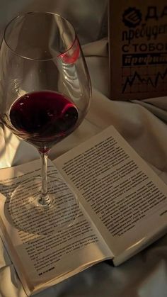 a glass of wine sitting on top of an open book