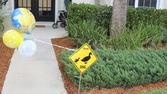 some balloons are tied to a sign in front of a house with a duck on it