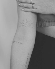 a woman's arm with a small sun tattoo on the left side of her arm