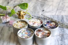 four tins filled with different types of flowers on top of a marble countertop