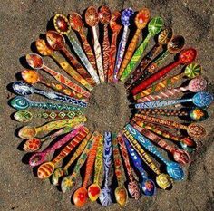 a circular arrangement of spoons arranged in the shape of a circle on top of sand