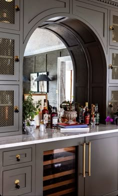 a bar with lots of bottles and glasses on top of it in front of a mirror